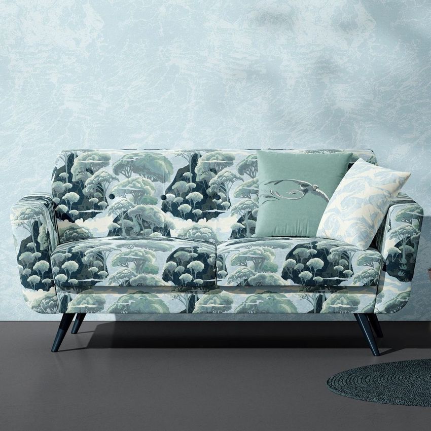 Modern sofa mockup featuring a patterned fabric with green and white tree motifs, styled with two decorative pillows on a gray floor.