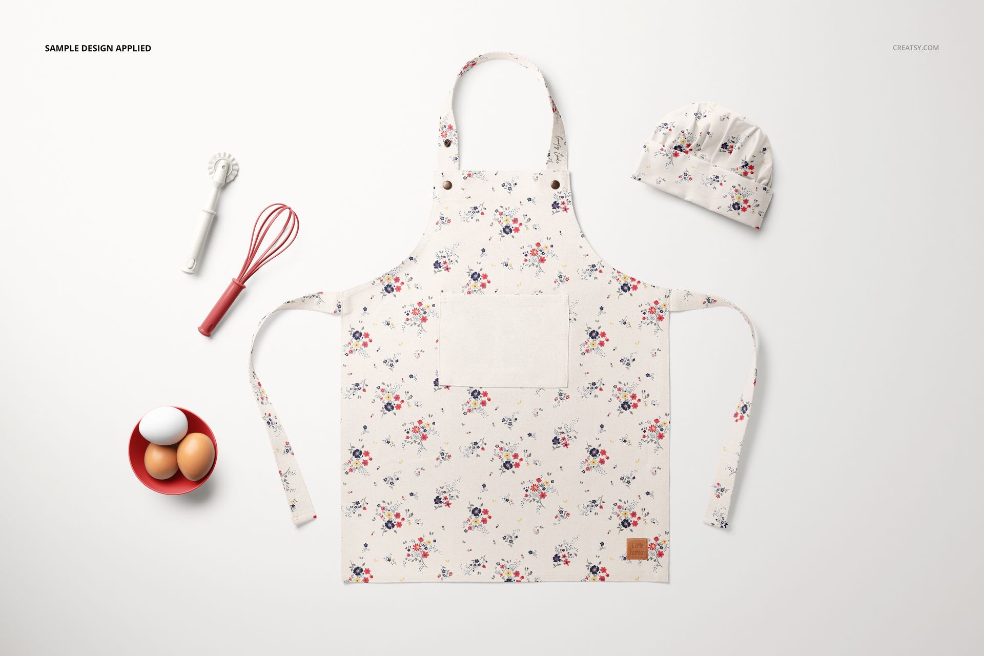 Kids apron mockup set featuring a light-colored apron with small floral prints, chef hat, and baking props arranged nearby.