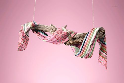 PSD mockup showing a patterned habotai silk scarf with hand-rolled borders arranged on driftwood, pink background.