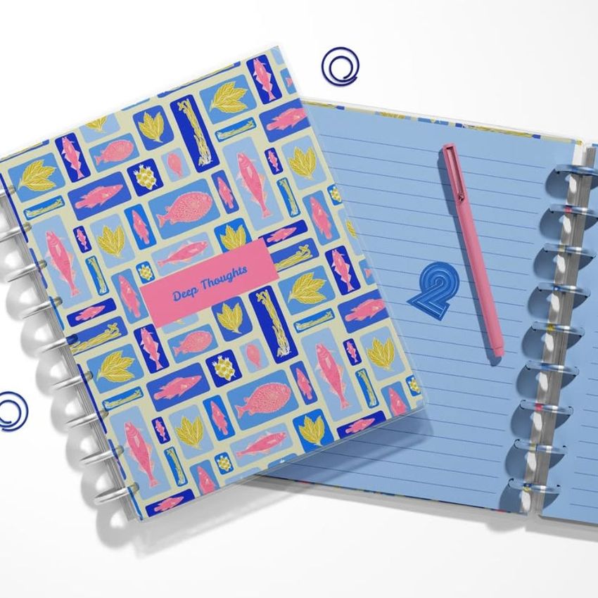 Two spiral-bound planner mockups seen from above, featuring a vibrant cover design and open pages with a pen resting on one.