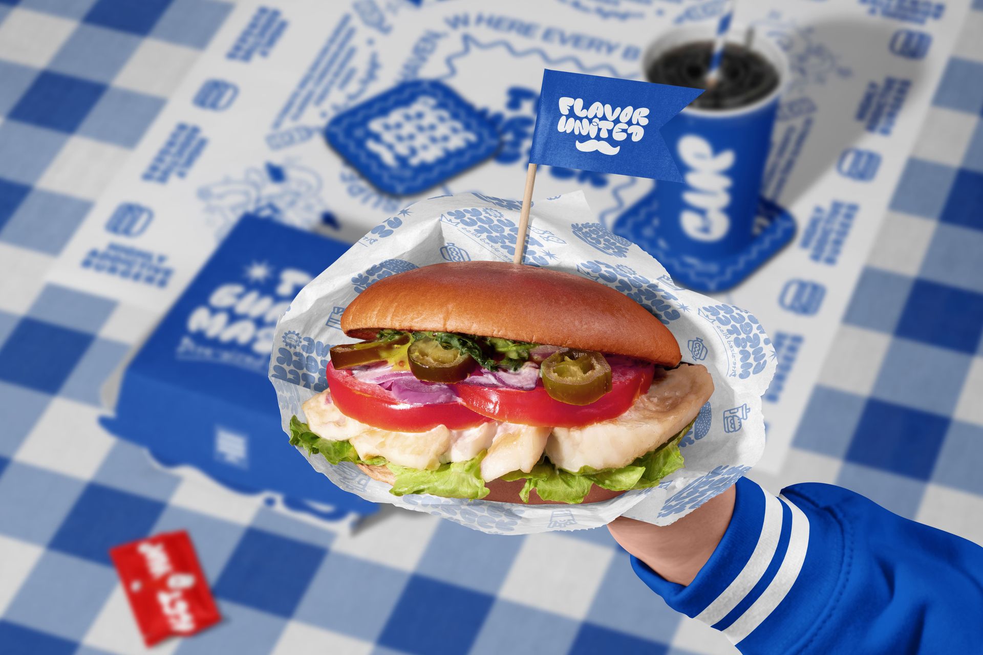Close-up of a vegan burger mockup in branded paper, featuring fresh toppings and blue packaging in the background.