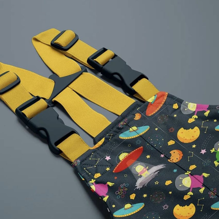 Kids rainwear mockup showing yellow adjustable straps and a dark fabric with colorful space-themed patterns and cartoon aliens.