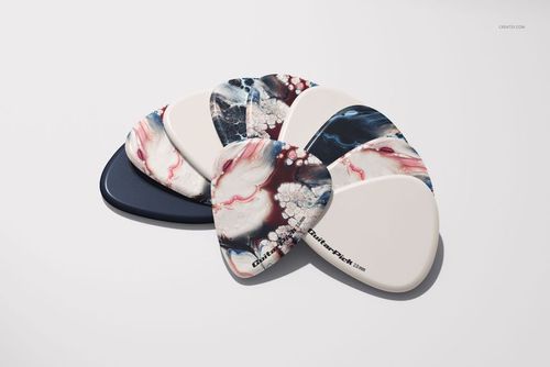 PSD mockup showing assorted guitar picks, some with artistic abstract designs and others in solid shades, laid out side by side.