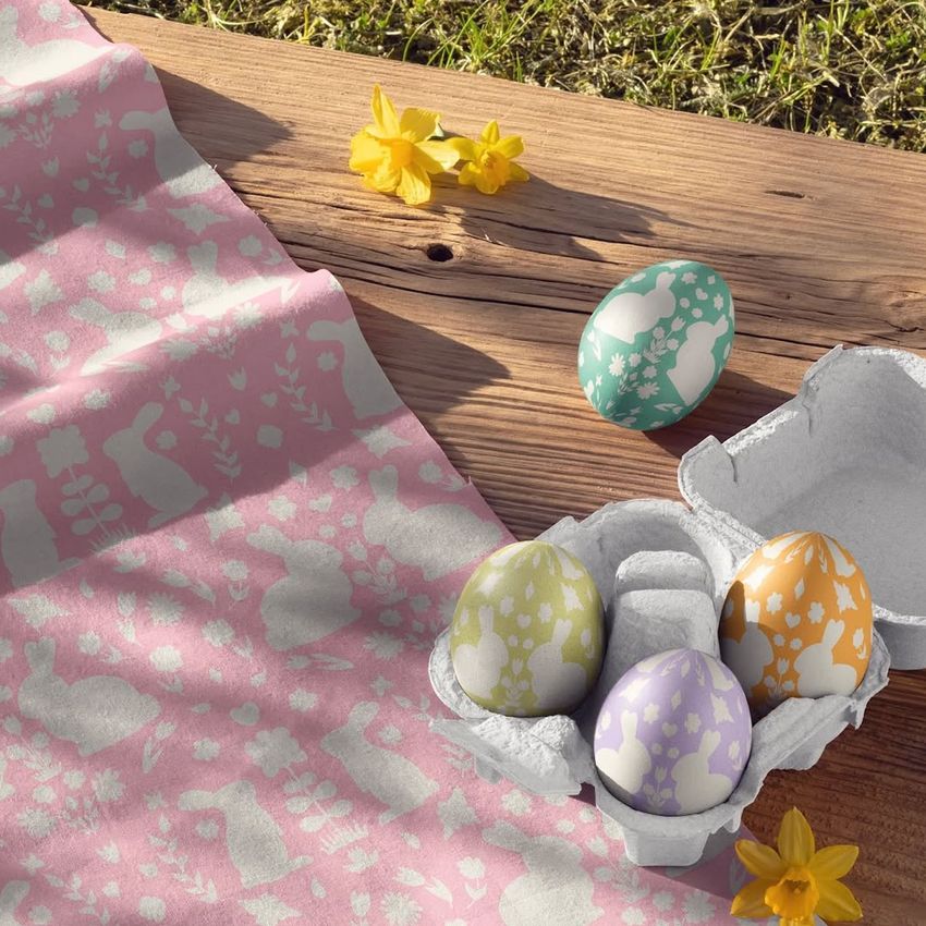 Cotton fabric mockup with a pink bunny and floral pattern displayed beside pastel Easter eggs in a carton on a wooden surface.