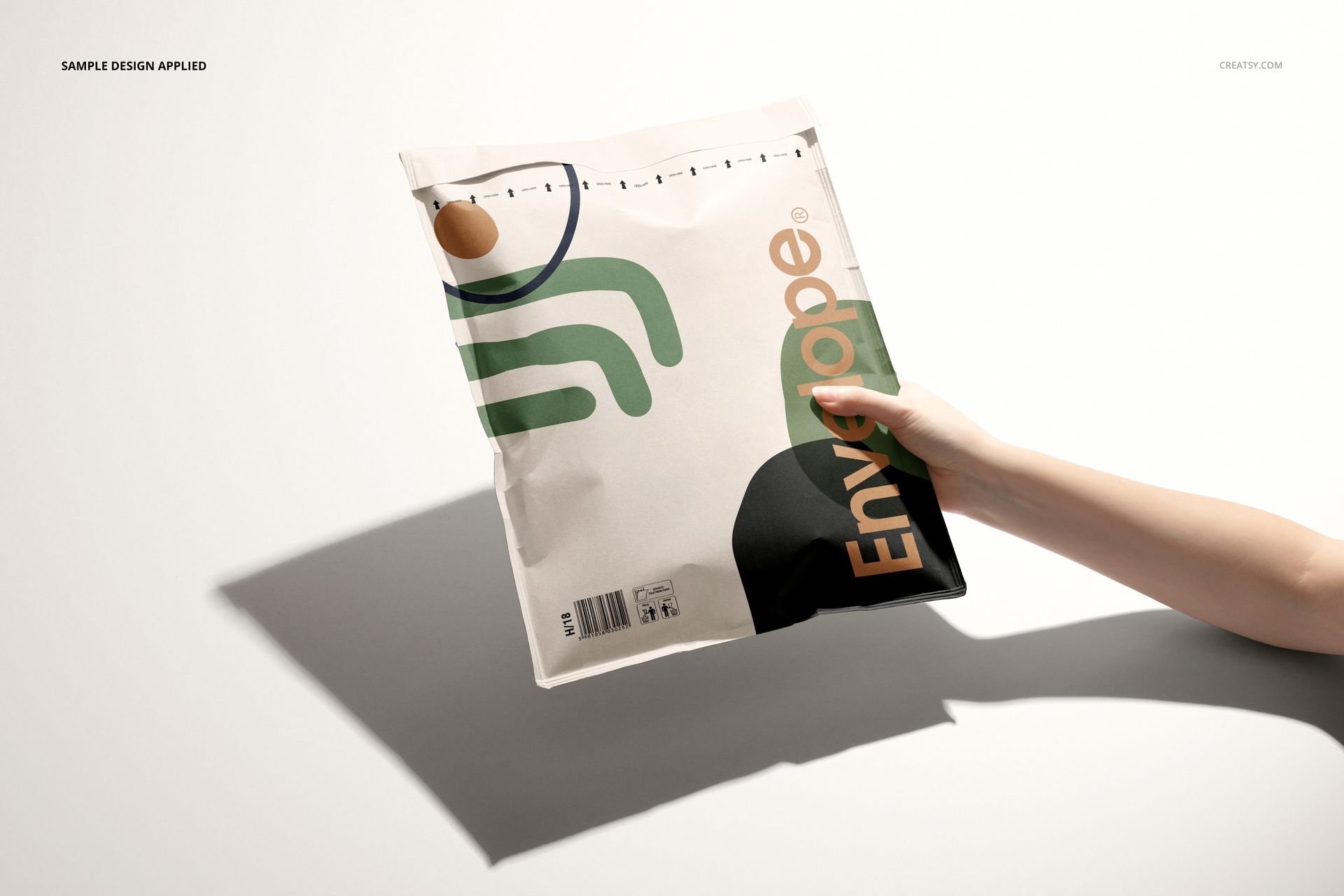 Front view of a kraft bubble mailer mockup featuring a colorful graphic design, held by a person's hand.