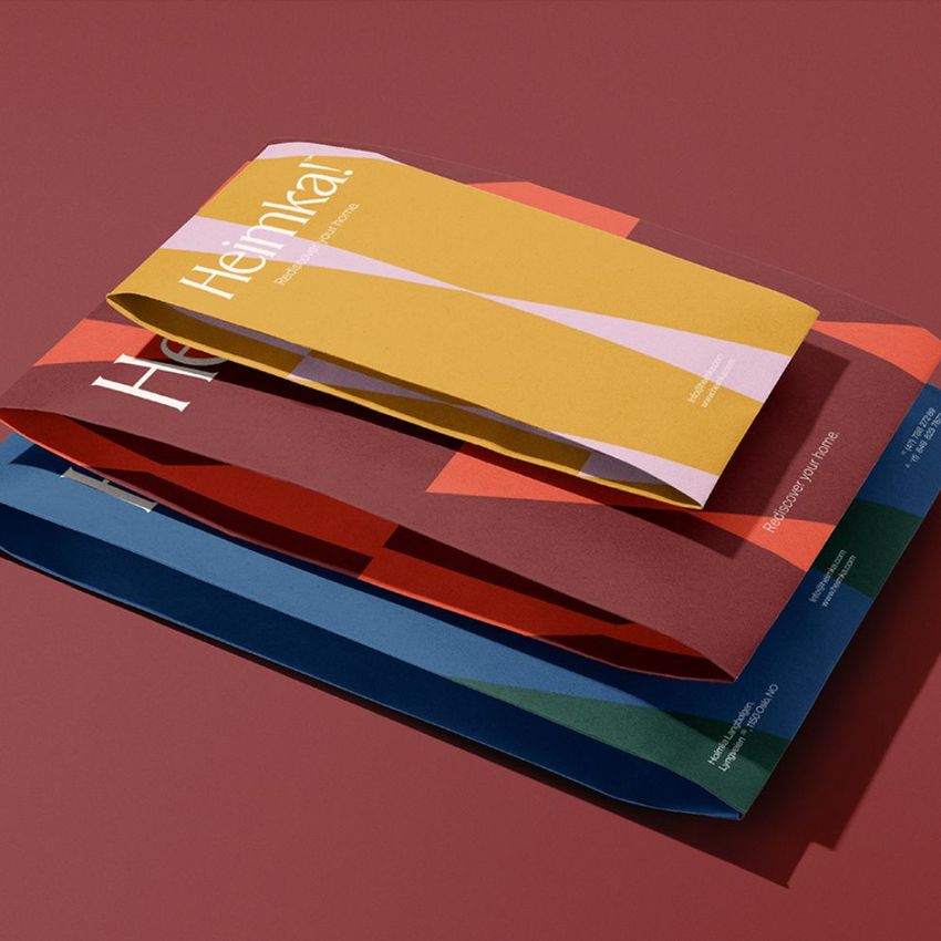 Kraft mailer mockup featuring three colorful mailers in yellow, red, and blue, arranged on a muted red background.