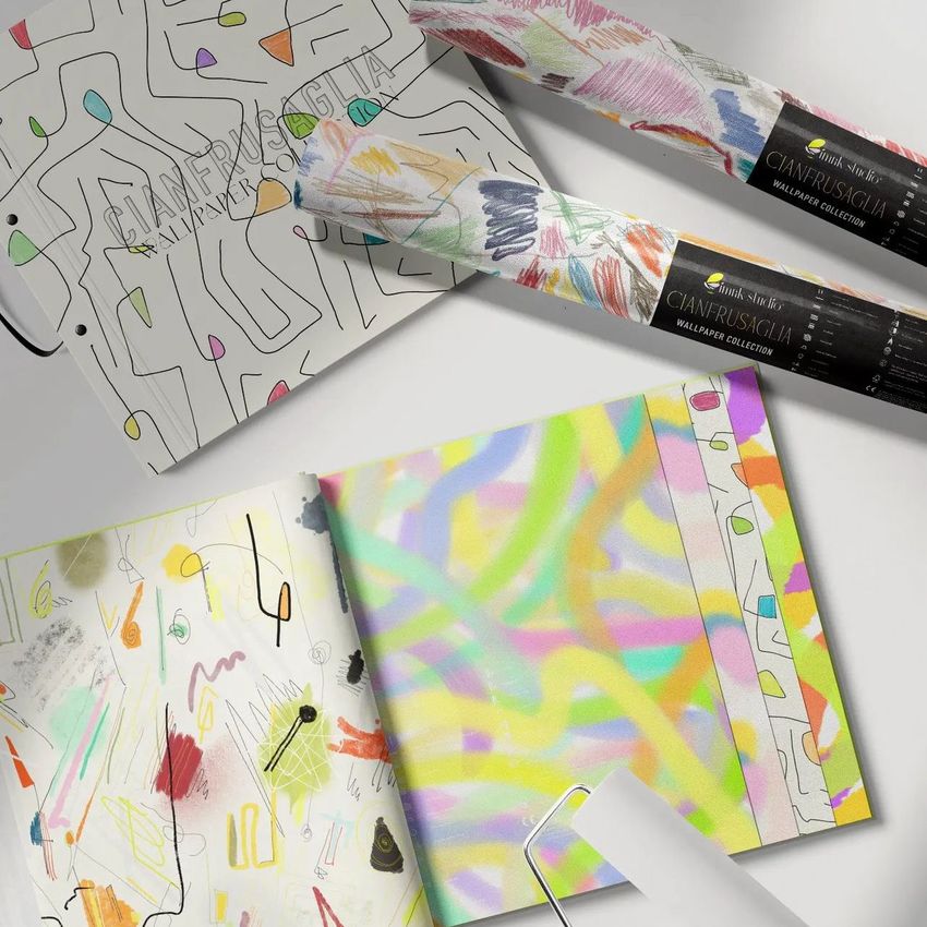 Wallpaper sample book mockup with open pages showing colorful abstract patterns and rolled wallpaper samples on a light surface.