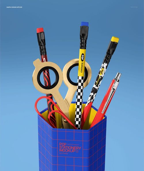 Close-up of a stationery mockup featuring a blue grid-patterned container with pencils, scissors, and a metal clip.