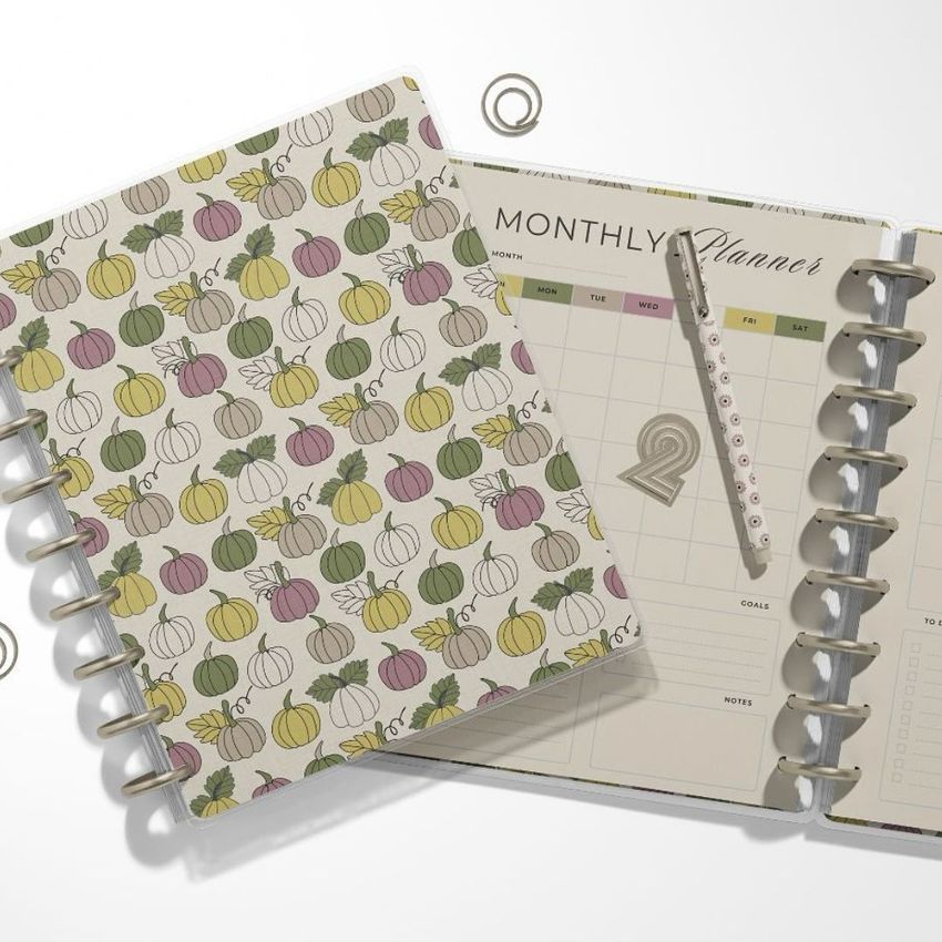 Stationery mockup featuring a patterned spiral notebook and an open planner with a calendar page, pen, and metal clips on a white background.