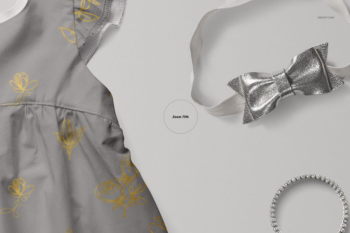 PSD mockup featuring a baby dress in gray with yellow flower motifs, displayed with a metallic bow and bracelet.