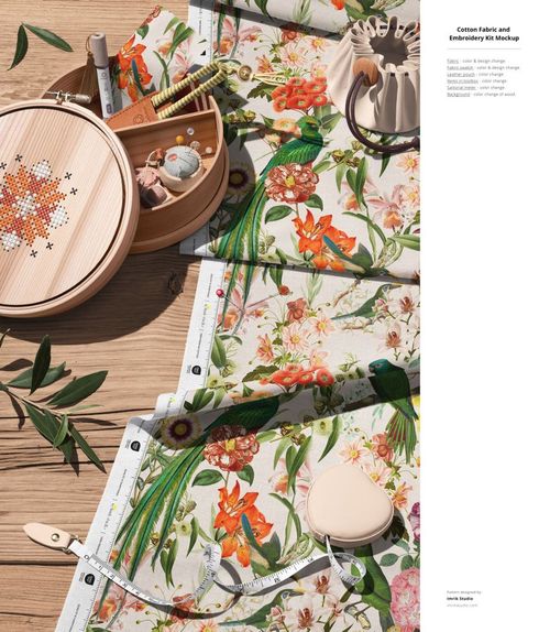 PSD mockup showing cotton fabric with vibrant flowers and birds, accompanied by sewing accessories and embroidery supplies.
