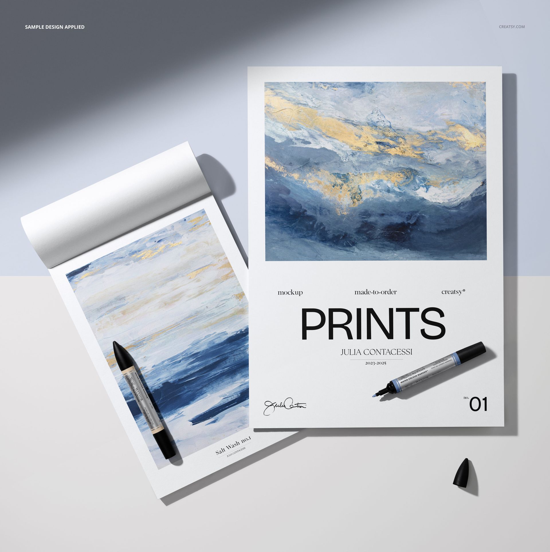 PSD mockup showing a spiral sketch pad and a flat poster-style sheet with painted designs and markers on a desk.