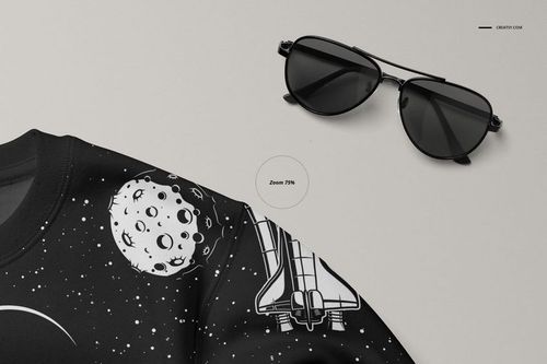 Close-up front view of a black baby sweatshirt mockup with white space-themed graphics, next to black sunglasses.