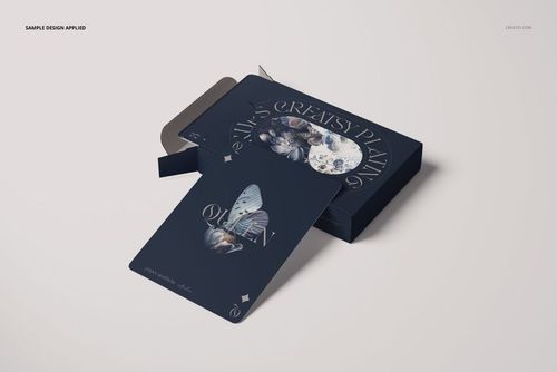 PSD mockup showing a custom playing card with butterfly and floral illustration, half-removed from a navy blue package.