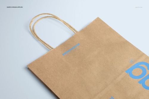 Natural kraft shopping bag mockup with twisted paper handles, shown from a top angle on a light surface.