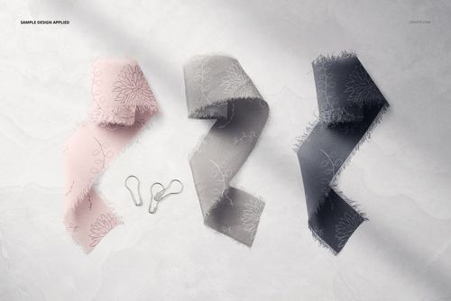 PSD mockup showing three frayed-edge silk ribbons in soft pink, gray, and charcoal, laid out on a marble surface.