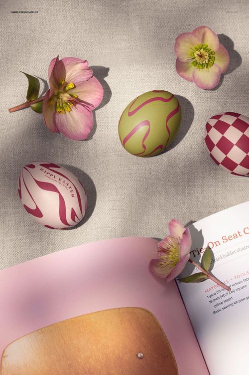 PSD mockup featuring patterned Easter eggs in pink and green alongside an open book and hellebore flowers.