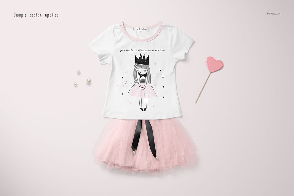 Front view of a girls t-shirt and pink tulle skirt mockup set, displayed on a light background with small props.