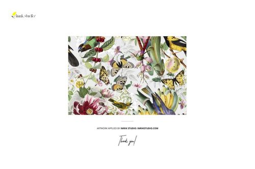 PSD mockup of patterned fabric with birds, butterflies, and flowers displayed outdoors on a green hedge under clear sky.