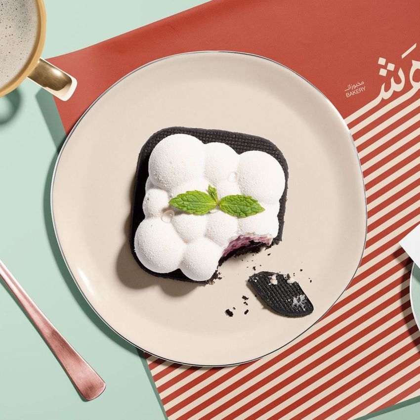 Food safe paper mockup featuring a dessert with white mousse and mint leaves on a plate, set on striped packaging paper.