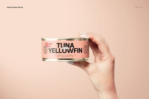Short flat tin can mockup shown in a hand, with a pink label, metallic rim, and minimalist background for packaging design.