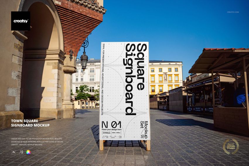 Rectangular signboard mockup displayed upright in a town square, surrounded by historic buildings and market stalls.