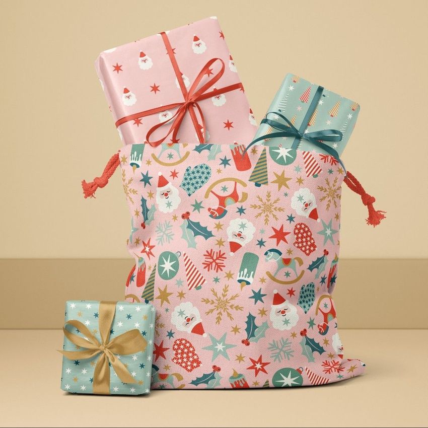 Santa bag mockup featuring a festive drawstring sack with colorful Christmas patterns, filled with wrapped presents on a beige background.
