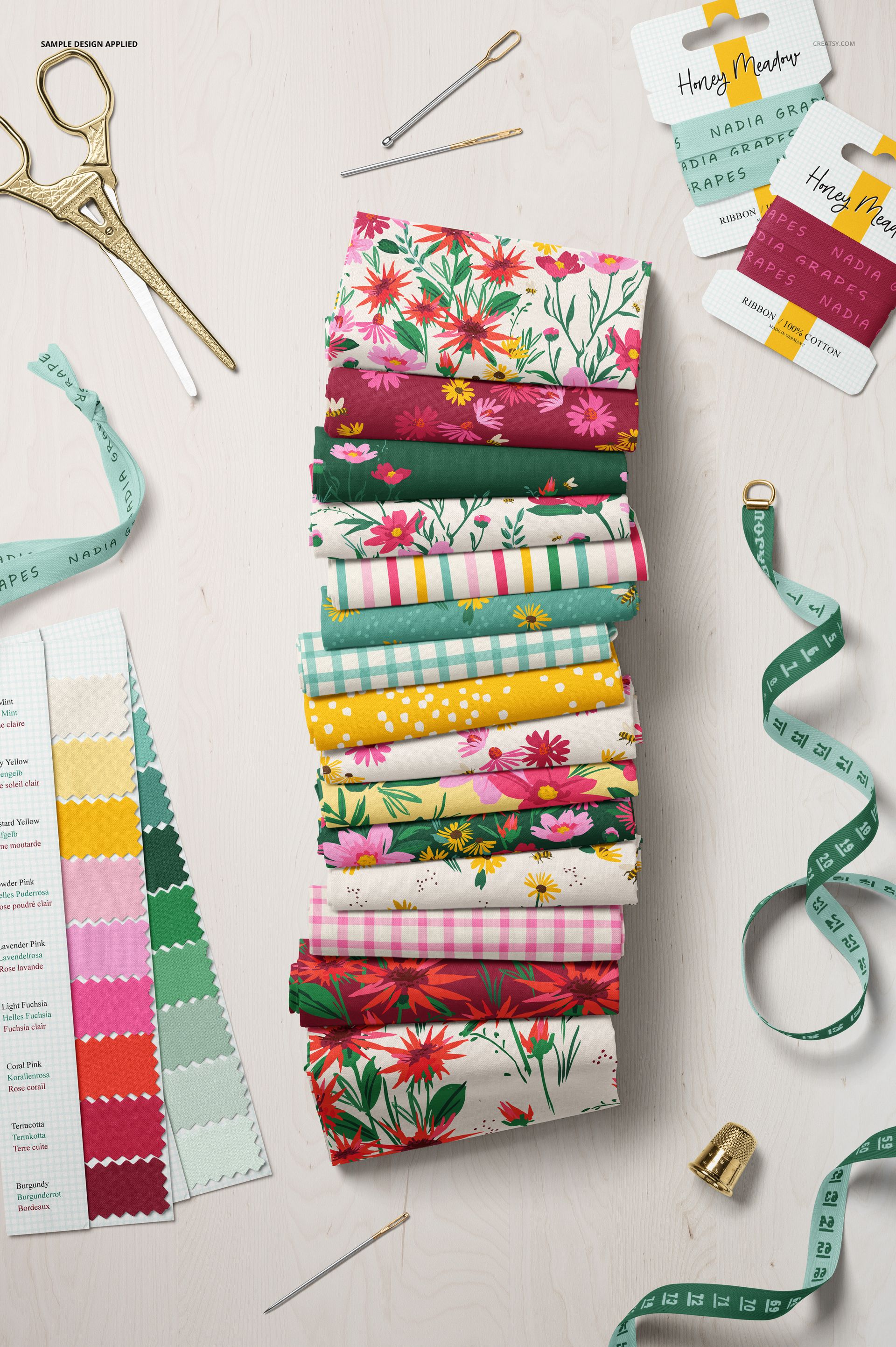 Cotton fabric mockup featuring various folded textiles with bright designs, swatch card, and sewing accessories.