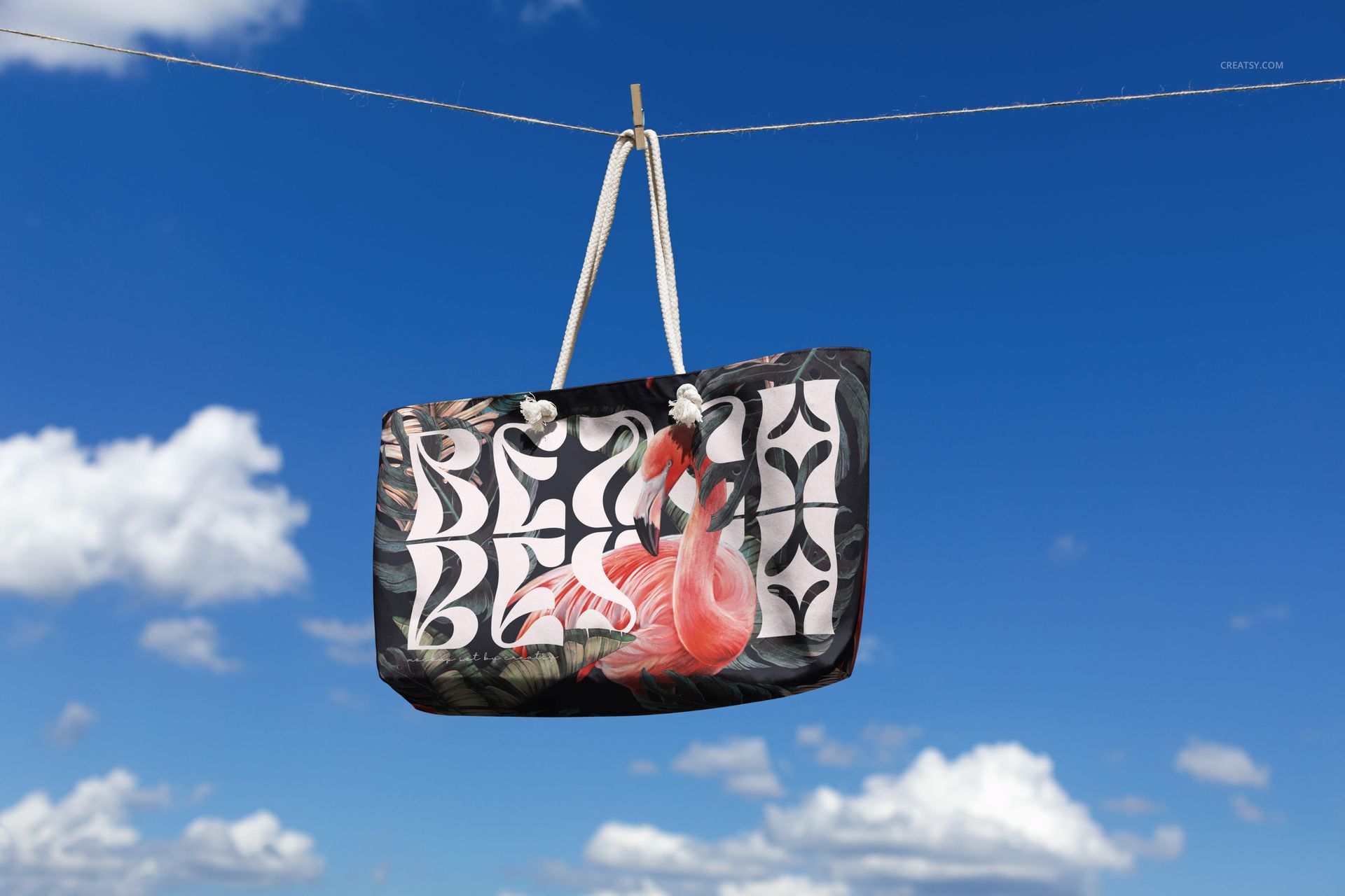 Spun polyester weekender bag mockup suspended on a clothesline, featuring bold patterns and tropical design.