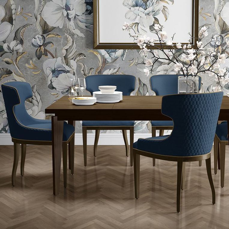Dining room interior mockup featuring a wooden table with stacked white dishes, blue upholstered chairs, and floral wallpaper.