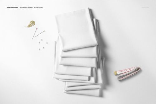 Top view of a fabric stack mockup featuring neatly folded white textiles and scattered sewing accessories.