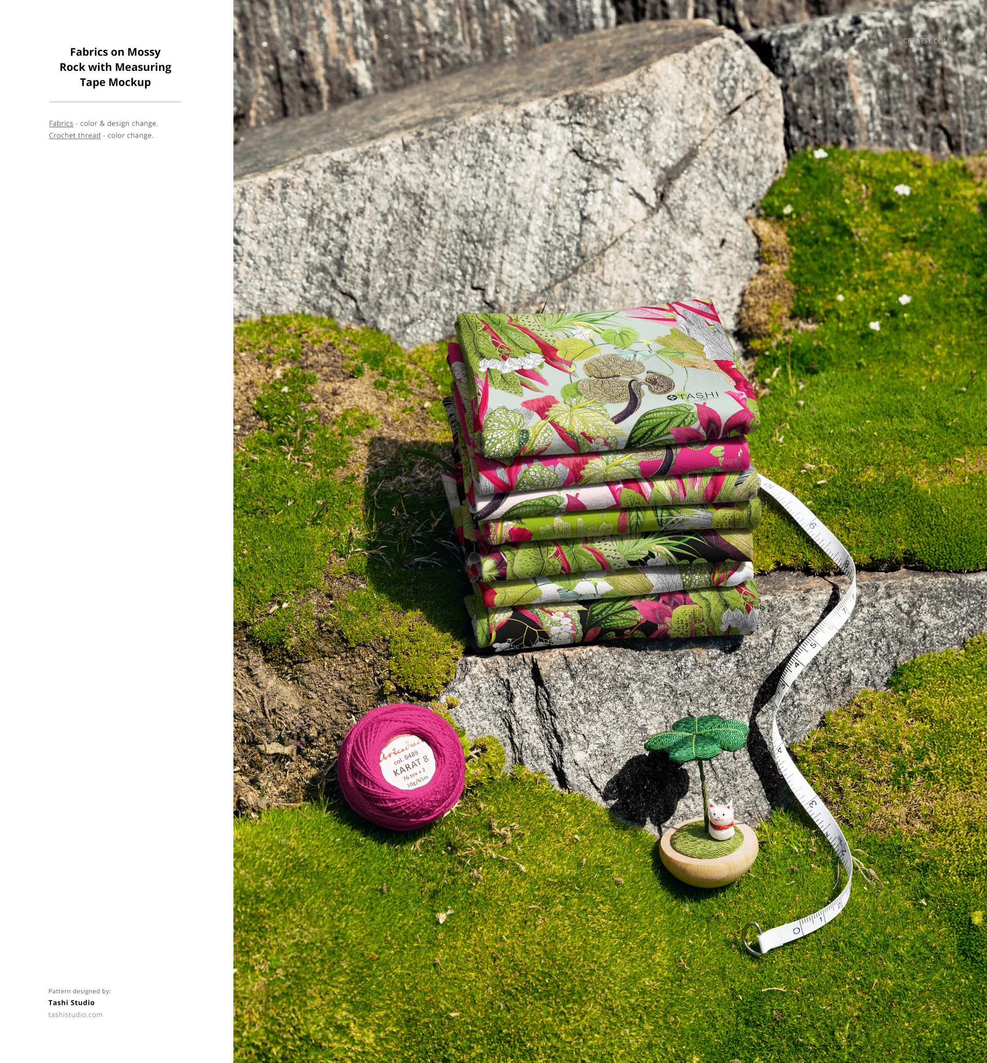 PSD mockup showing colorful floral fabric stack outdoors on mossy stone, with sewing props and measuring tape beside.