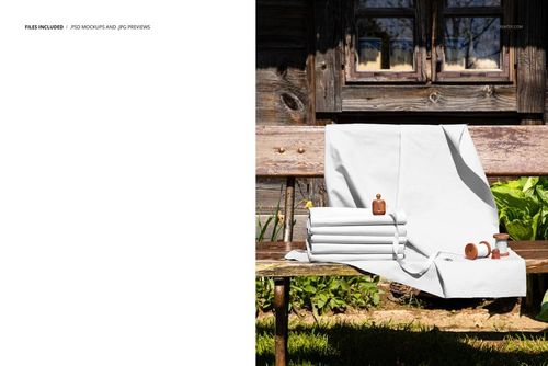 PSD mockup showing plain white textiles arranged on a wooden bench, accompanied by spools and wooden accessories outdoors.