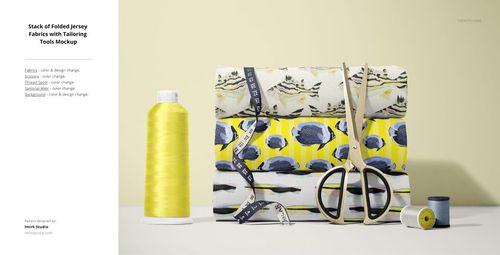 PSD mockup showing folded patterned jersey fabrics, scissors, measuring tape, and sewing thread on a neutral background.