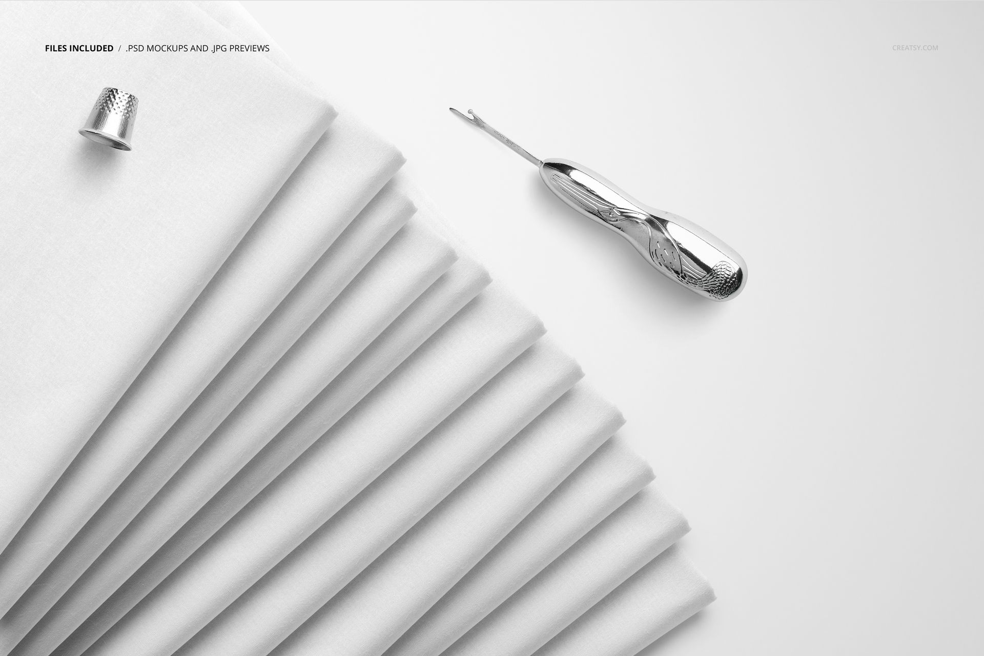 Top view of multiple folded fabrics in white, placed on a plain surface with sewing accessories, for PSD mockup use.