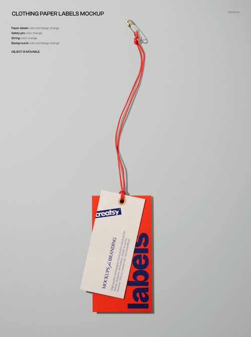Close-up of a branding mockup showing layered paper labels in red and white, joined by a red cord and pin.