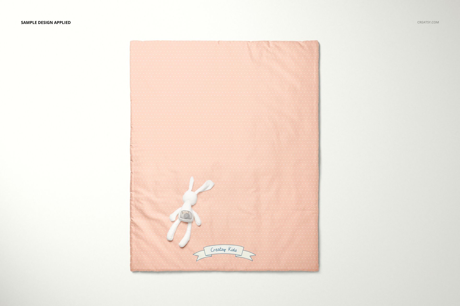 Flat lay of a peach baby duvet cover mockup with a small white stuffed rabbit and a decorative banner at the bottom.