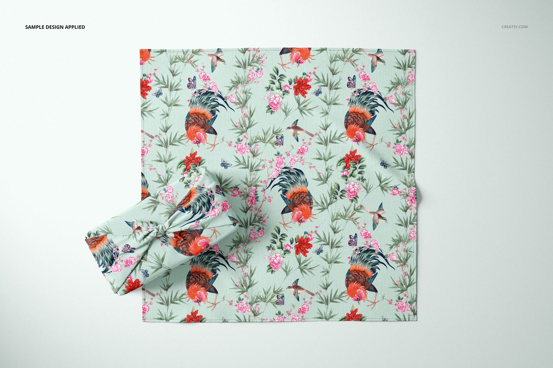 Top view of a Furoshiki fabric wrap mockup featuring a colorful design with flowers and roosters on a pale background.