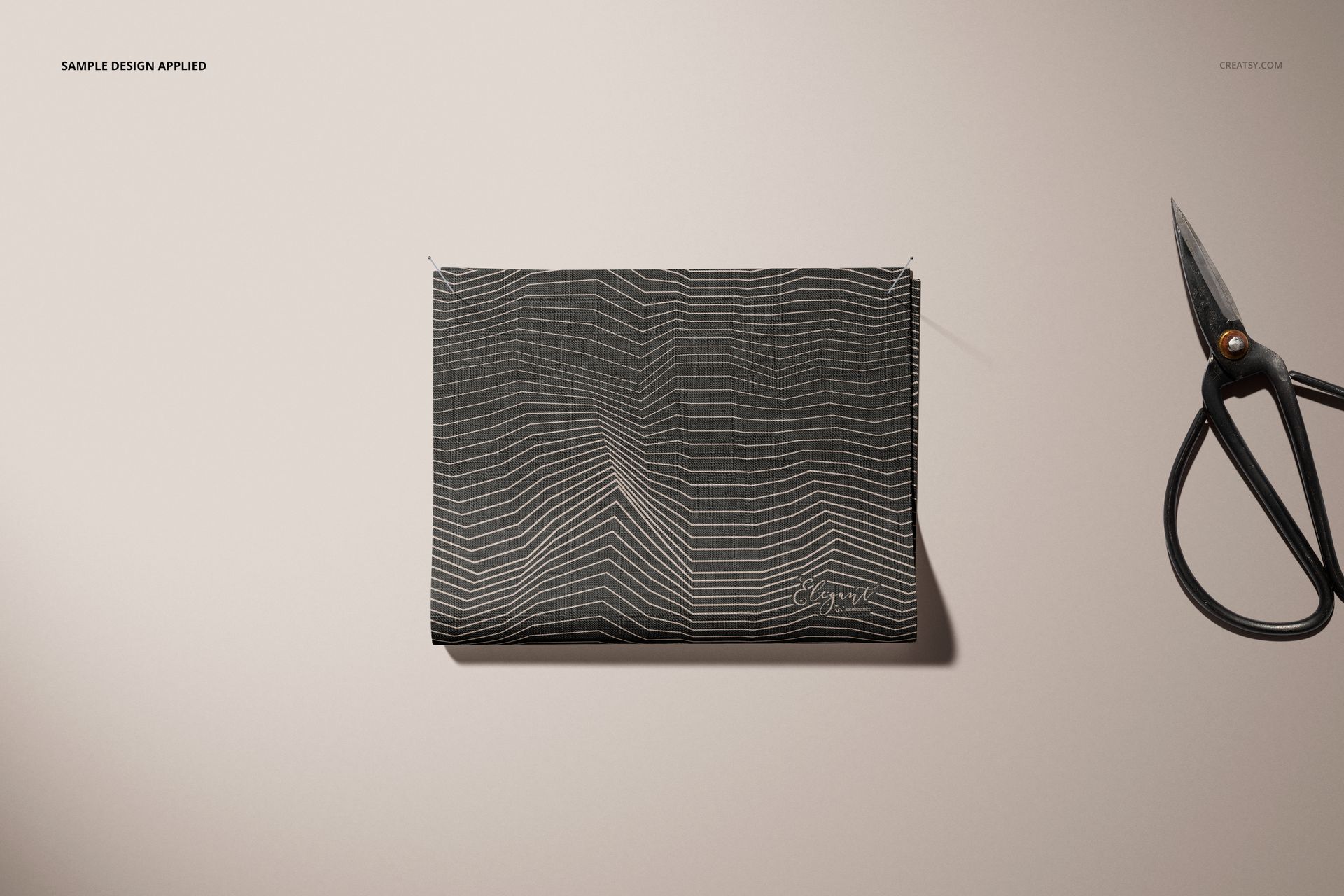 Mockup of a fabric sample with abstract linear design, displayed flat with visible pins and scissors on a neutral background.