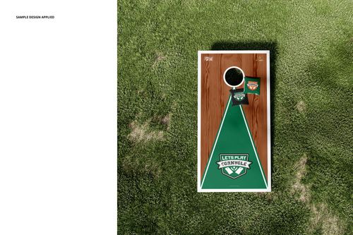 Cornhole board mockup set displayed outdoors on grass, showing a rectangular board with green and wood accents.