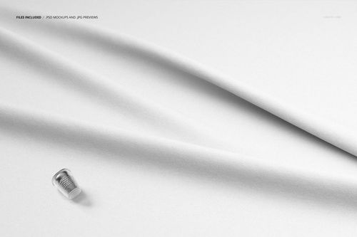Top view of smooth white textile with gentle creases and a silver thimble placed near the edge, fabric mockup scene.