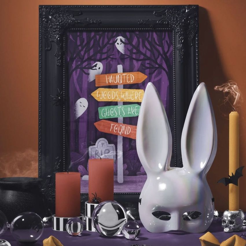 Halloween picture frame mockup displaying a haunted woods art print with ghosts, candles, and festive props on a table.
