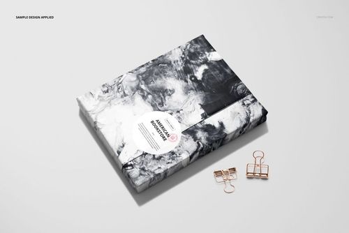 PSD mockup of a book covered in abstract black and white wrapping paper, displayed on a plain background with binder clips.