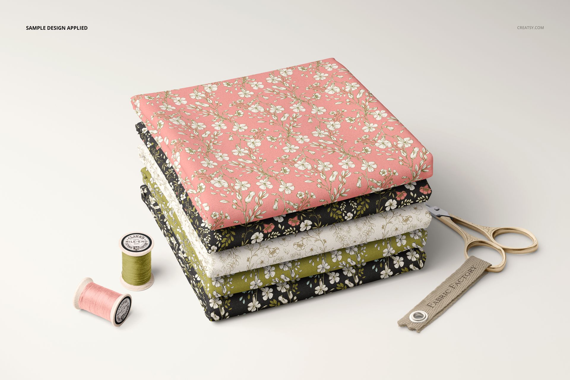 Fabric stack mockup featuring four folded textiles with small floral prints in pastel and dark shades, viewed from the front.
