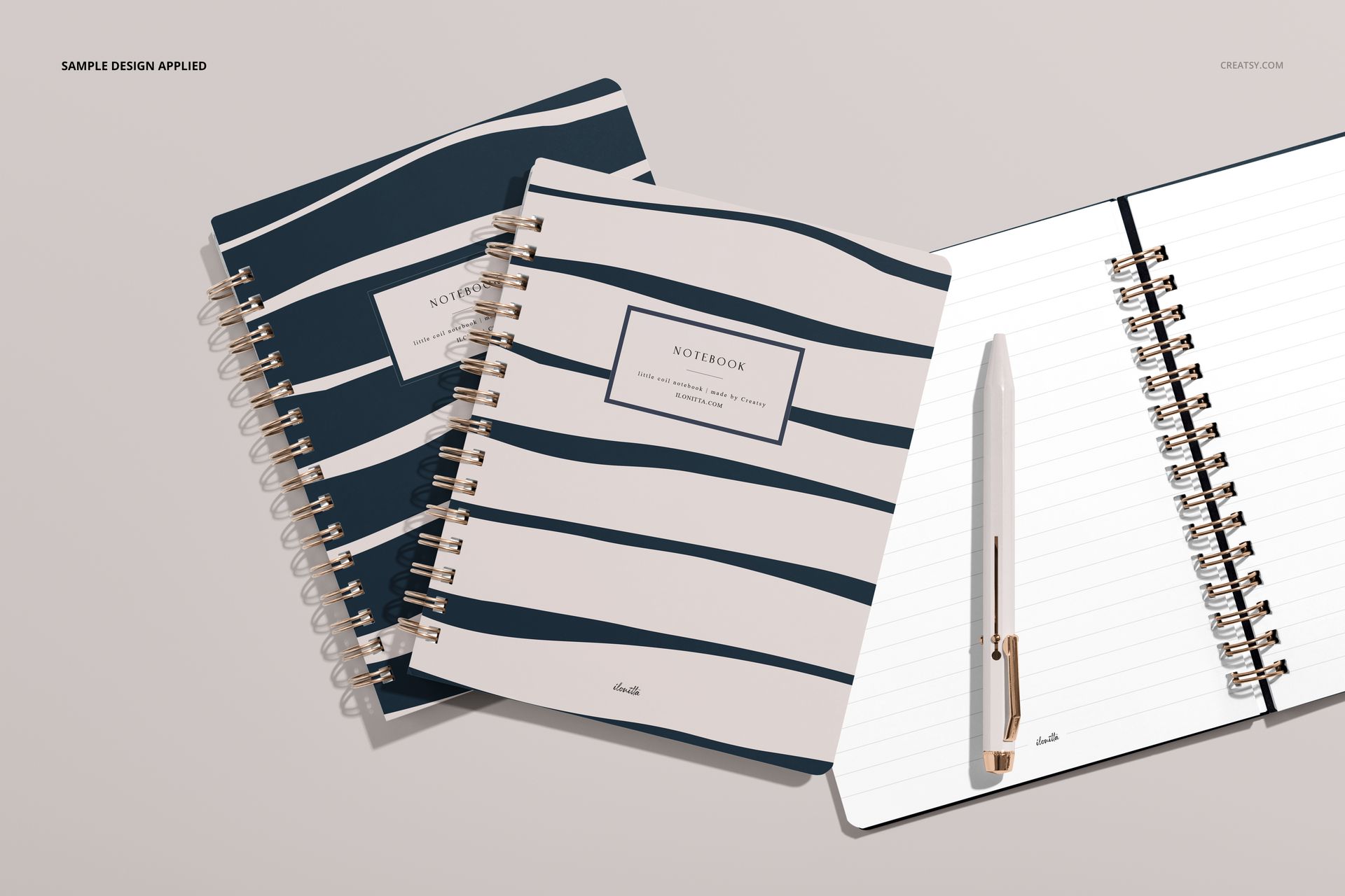 Little coiled notebook PSD mockup featuring two closed notebooks with dark blue stripes and one open beside a pen.
