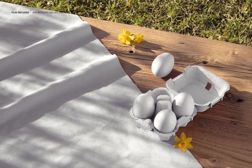 Cotton fabric mockup displayed on a wooden surface with white Easter eggs and yellow flowers in natural sunlight.