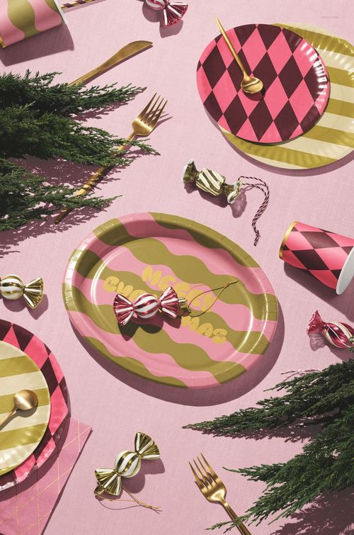 Top view of a mockup table setting with an oval striped paper platter, diamond-patterned plates, gold cutlery, and wrapped candies.