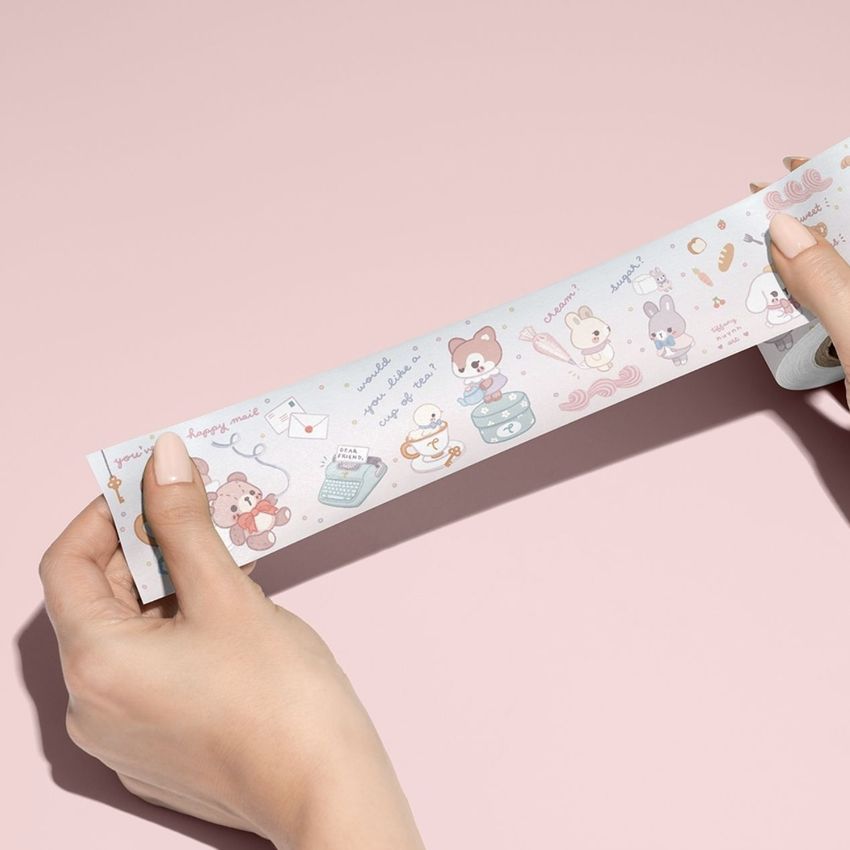 Decorative packing tape mockup with whimsical animal designs being held and displayed against a smooth, pale pink background.