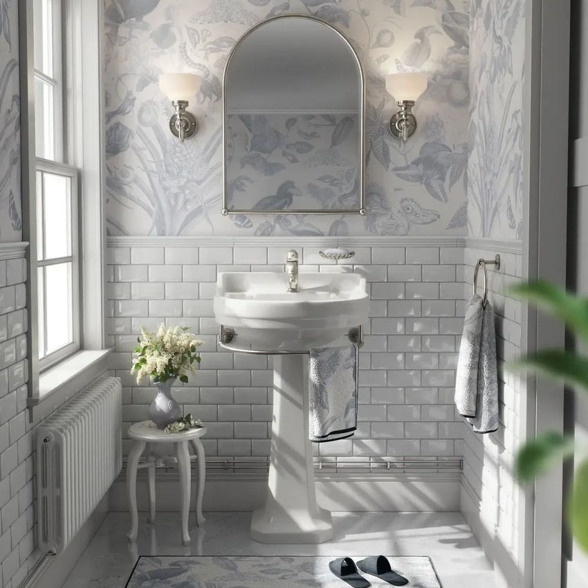 Vintage retro bathroom mockup showing a pedestal sink, arched mirror, and floral wallpaper with white tile walls.