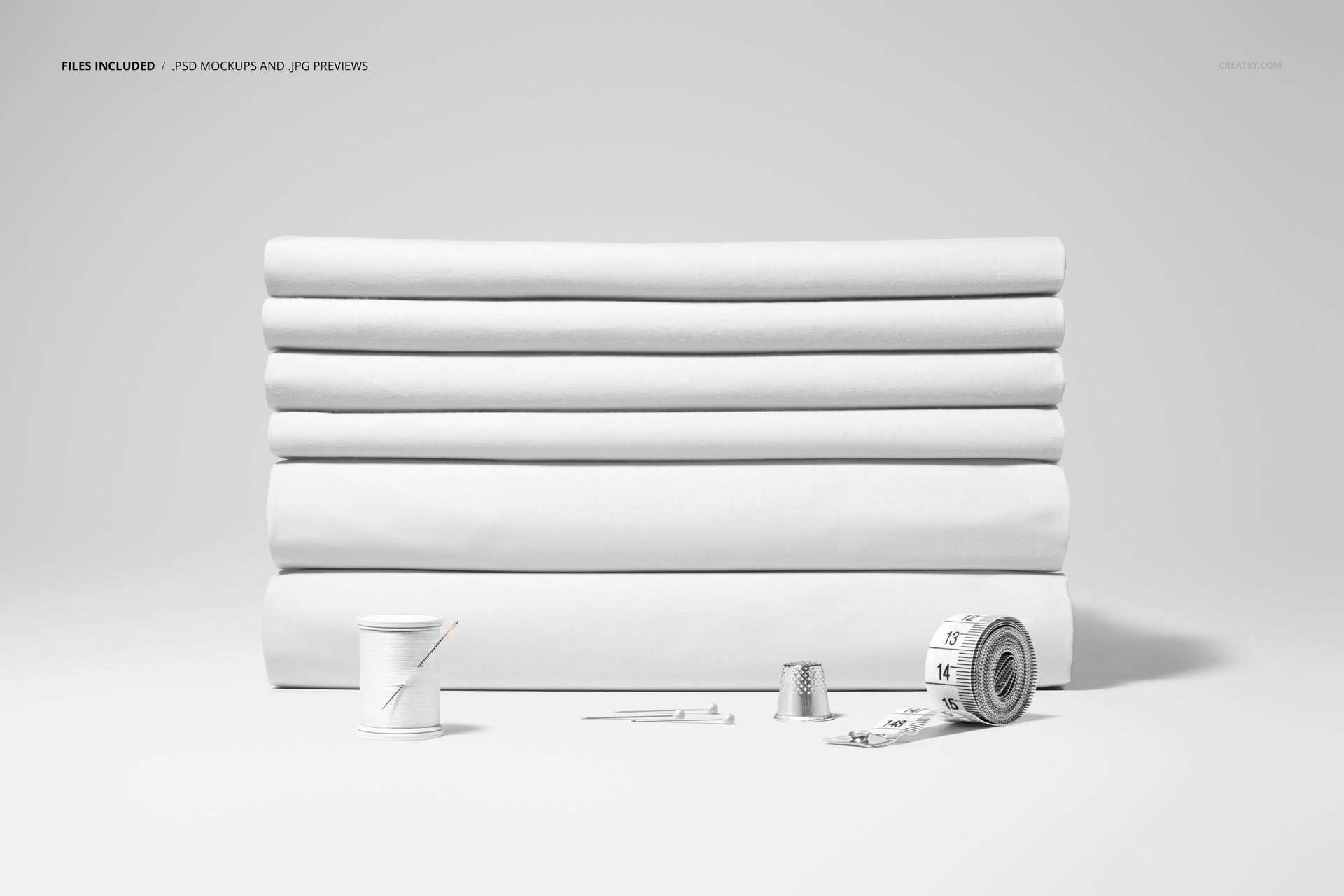 Folded fabrics mockup featuring plain white textiles stacked in a row, accompanied by sewing accessories on a neutral background.